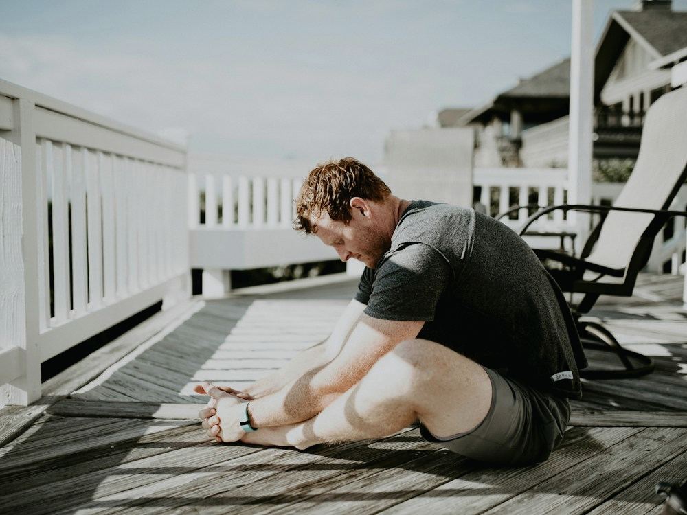 A man stretching on a deck in the morning light