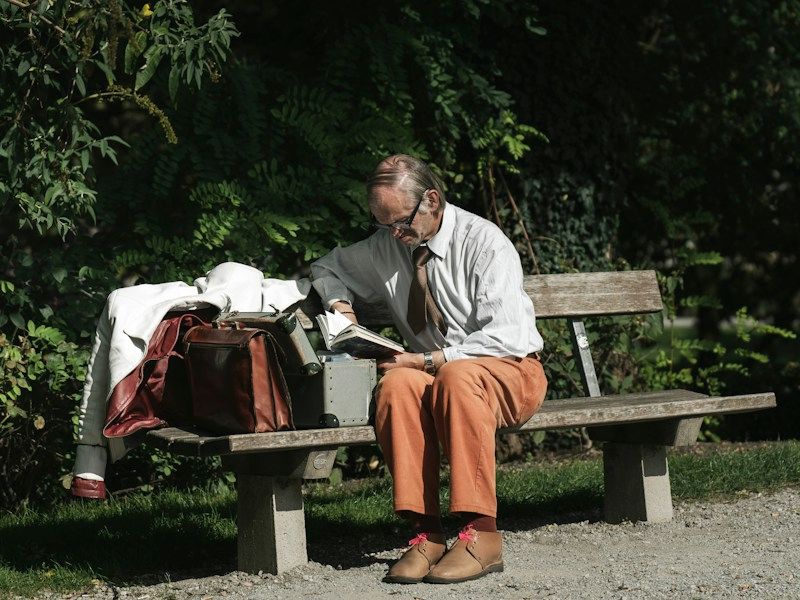 An older man reading on a park bench