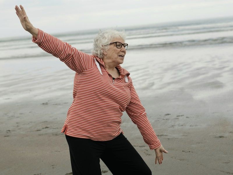 An older woman stretching on a beach