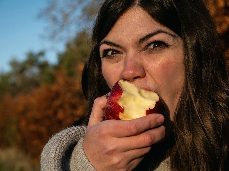 A woman eating an apple outdoors