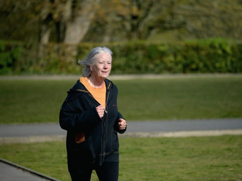 A woman running along a path through a park
